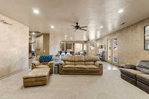 Living area with ceiling fan, french doors, recessed lighting, and a textured wall