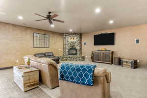 Living area featuring ceiling fan, recessed lighting, a fireplace, and a textured wall