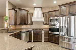 Kitchen with stainless steel appliances, dark wood finish cabinetry, light stone counters, and recessed lighting