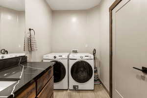 Laundry room featuring washing machine and clothes dryer and light wood finished floors