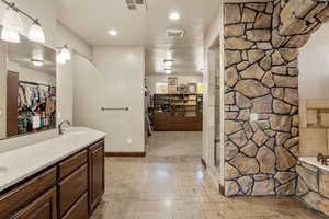 Bathroom featuring a walk in closet, double vanity, a garden tub, and recessed lighting