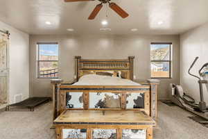 Carpeted bedroom with a barn door, recessed lighting, and ceiling fan