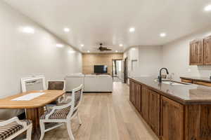 Kitchen with wood finish cabinetry, open floor plan, light wood-style floors, an island with sink, and recessed lighting