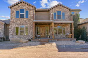 View of front of house with stone siding and a balcony