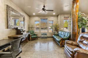 Living room featuring stone tile flooring, a ceiling fan, and recessed lighting