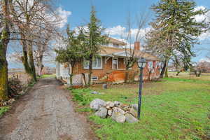 View of home's exterior with brick siding, a chimney, a yard, a shingled roof, and driveway