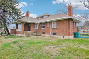 Rear view of house with a chimney and a lawn