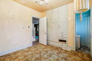 Unfurnished bedroom with suspended lighting and baseboards