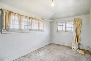 Unfurnished dining area with vaulted ceiling and baseboards