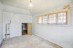 Empty room with vaulted ceiling and baseboards