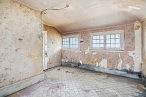 Spare room with vaulted ceiling and wallpapered walls