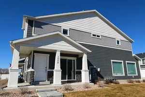 View of front facade featuring covered porch and stone siding