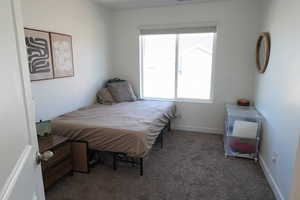 Bedroom featuring dark carpet and baseboards