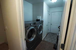 Laundry area featuring washing machine and clothes dryer, dark tile patterned floors, and a textured ceiling