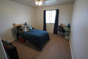 Bedroom featuring light carpet, ceiling fan, and a desk