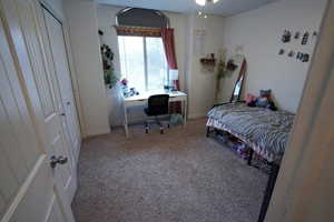 Bedroom with light carpet, a desk, and a closet