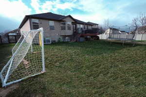Rear view of property featuring a fenced backyard, a trampoline, and a deck