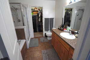 Bathroom with a walk in closet, a shower stall, and vanity