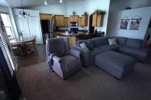 Living area with vaulted ceiling, a chandelier, and dark colored carpet