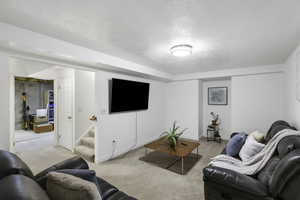 Living area with light carpet and a textured ceiling