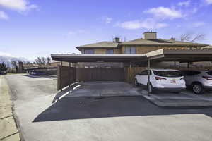View of front of property featuring a chimney, brick siding, and covered parking