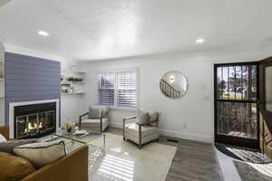 Living area featuring wood finished floors, a glass covered fireplace, and recessed lighting