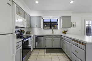 Kitchen featuring gray cabinetry, stainless steel appliances, a peninsula, light countertops, and ornamental molding