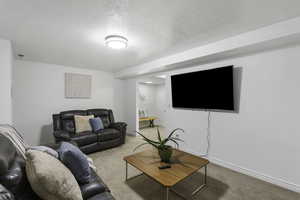 Carpeted living room with a textured ceiling and baseboards
