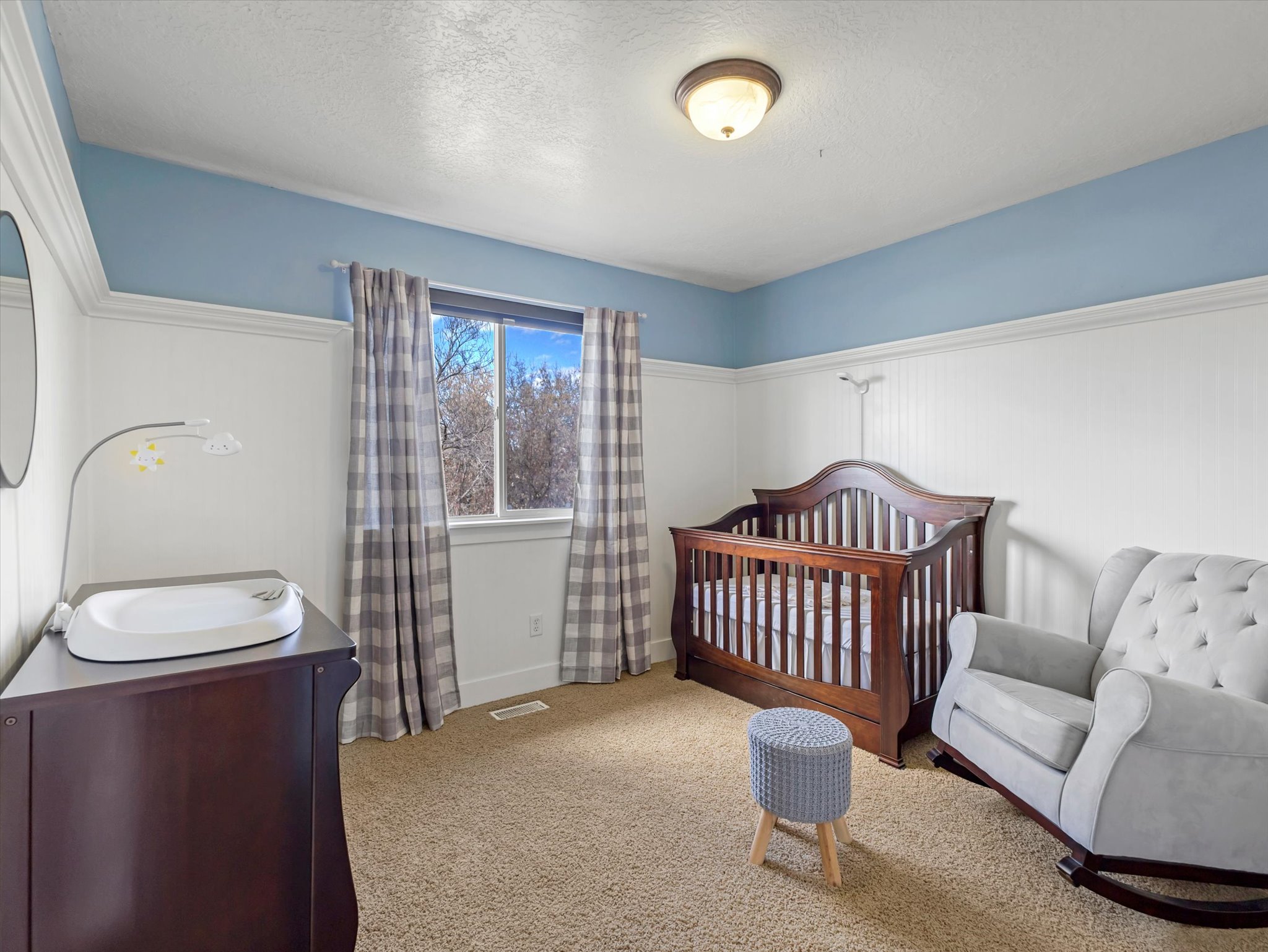 Bedroom featuring a nursery area, carpet floors, and a textured ceiling