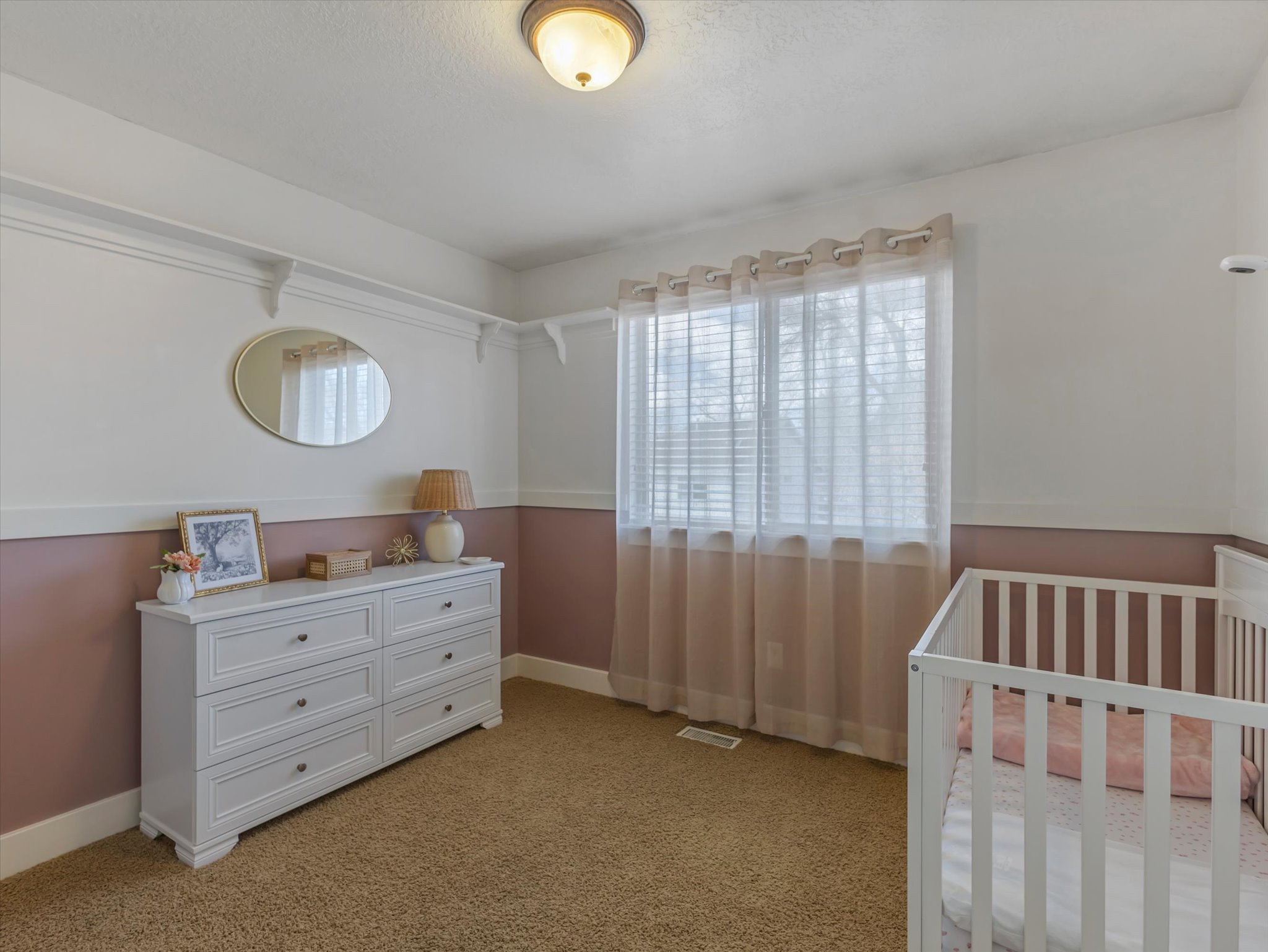 Bedroom featuring a crib and light carpet