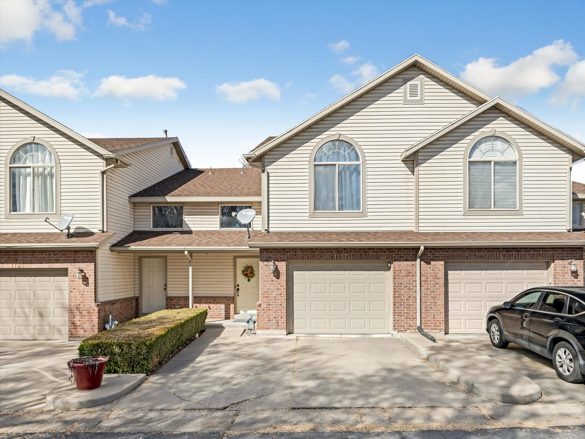 Traditional home featuring roof with shingles, an attached garage, brick siding, and driveway