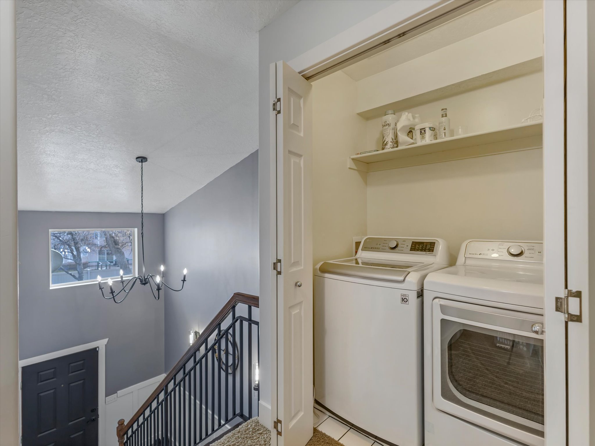 Laundry area featuring a textured ceiling, suspended lighting, independent washer and dryer, and light tile patterned floors