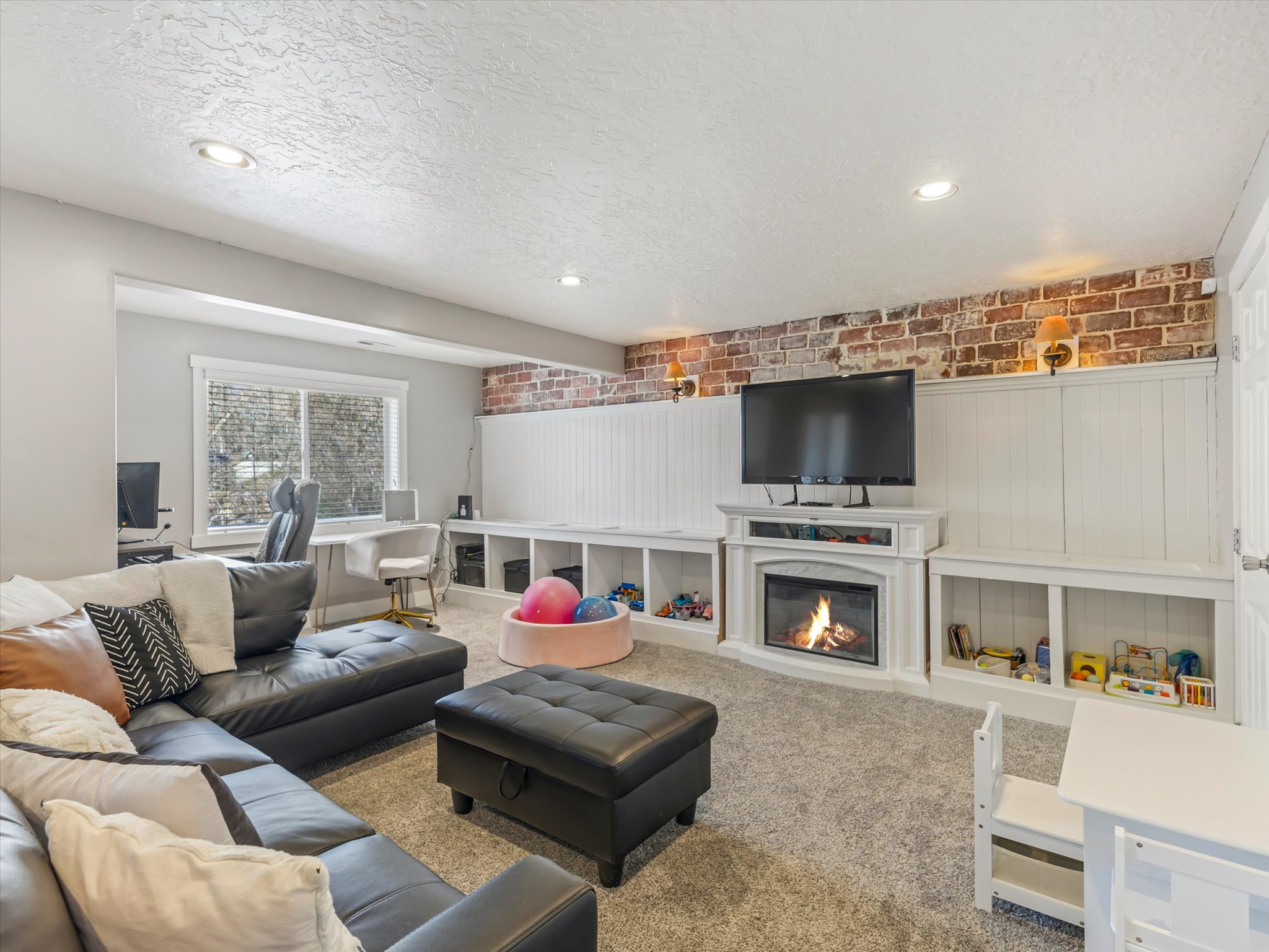 Living area with a fireplace, carpet, a textured ceiling, wainscoting, and recessed lighting