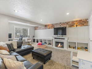Living area with a fireplace, carpet, a textured ceiling, wainscoting, and recessed lighting