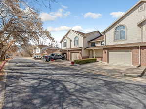 View of front of house with brick siding, driveway, a residential view, and a garage