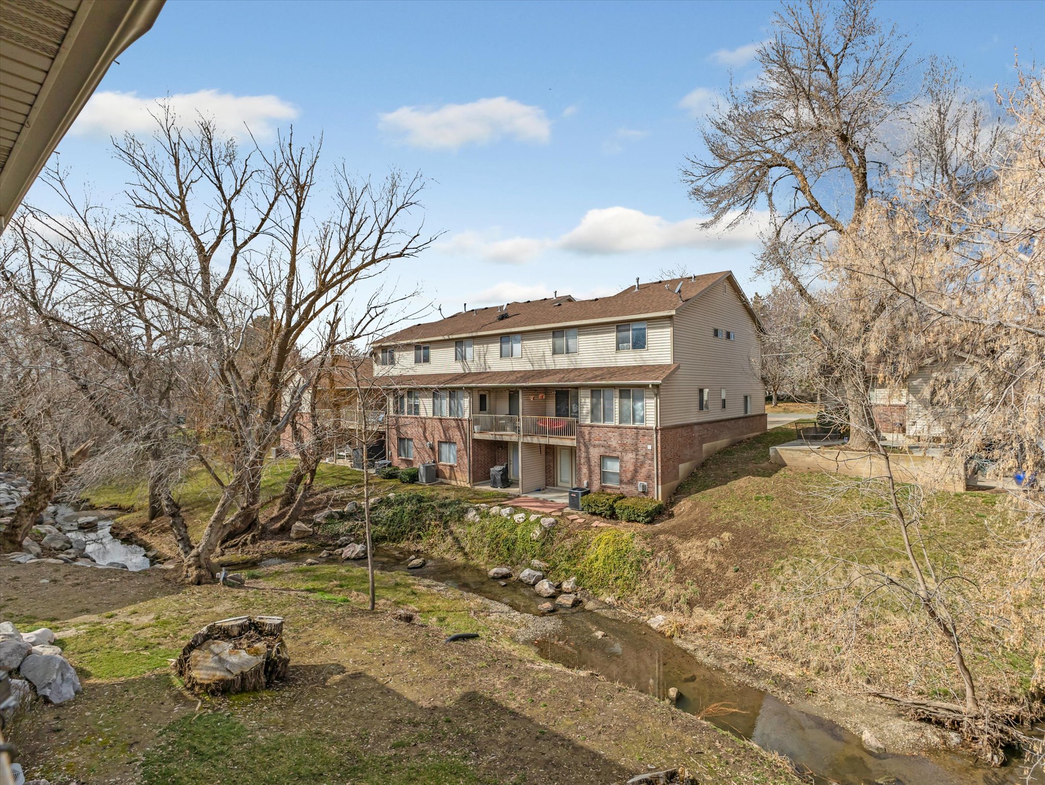 Back of house with a balcony, brick siding, and a water view