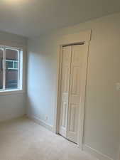 Unfurnished bedroom featuring light colored carpet and a closet