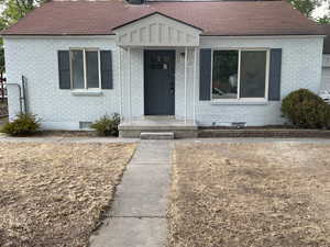View of front of property with brick siding, roof with shingles, and crawl space