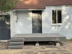 Entrance to property with a shingled roof and a deck