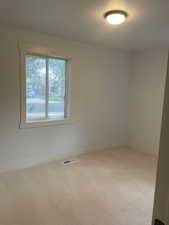 Spare room featuring light carpet and baseboards