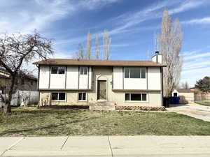 Raised ranch featuring brick siding, a chimney, stucco siding, and roof with shingles