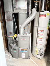 Utility room featuring heating unit and gas water heater