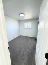 Unfurnished room featuring dark carpet and a textured ceiling