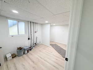 Below grade area featuring light wood finished floors, a paneled ceiling, and recessed lighting