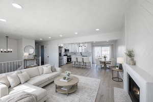 Living room featuring a fireplace with flush hearth, light wood-style flooring, and a chandelier