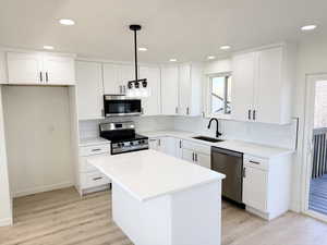 Kitchen featuring stainless steel appliances, a center island, light wood-type flooring, and white cabinets