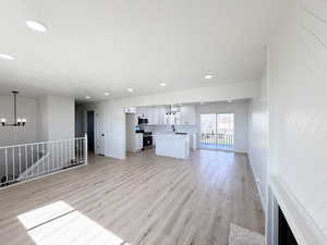 Unfurnished living room featuring light wood-style floors, suspended lighting, and a textured ceiling