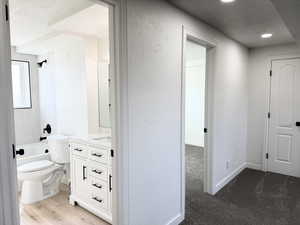 Full bathroom with a textured ceiling, vanity, a textured wall, shower / bathtub combination, and light wood-style flooring