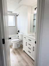 Bathroom featuring vanity, light wood finished floors, a textured ceiling, and shower / bath combination