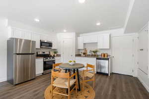 Kitchen featuring stainless steel appliances, white cabinets, dark wood-style floors, dark stone countertops, and recessed lighting